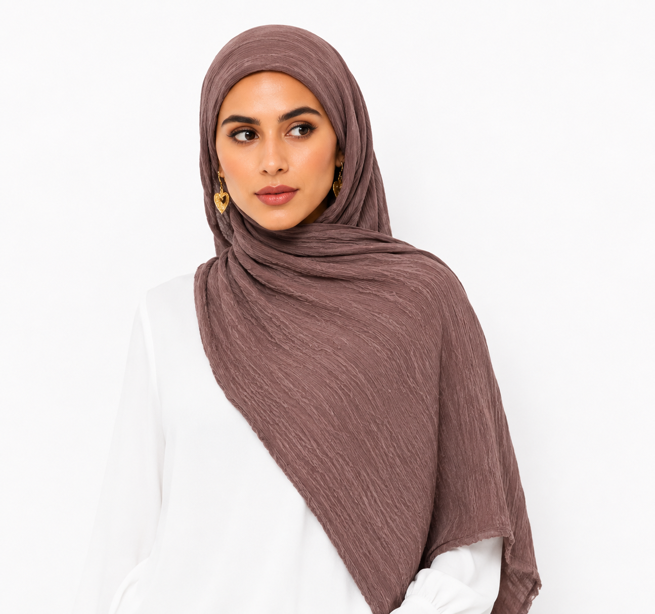 A woman wearing a textured, crinkled mauve-brown hijab and a white top, photographed against a clean white background.